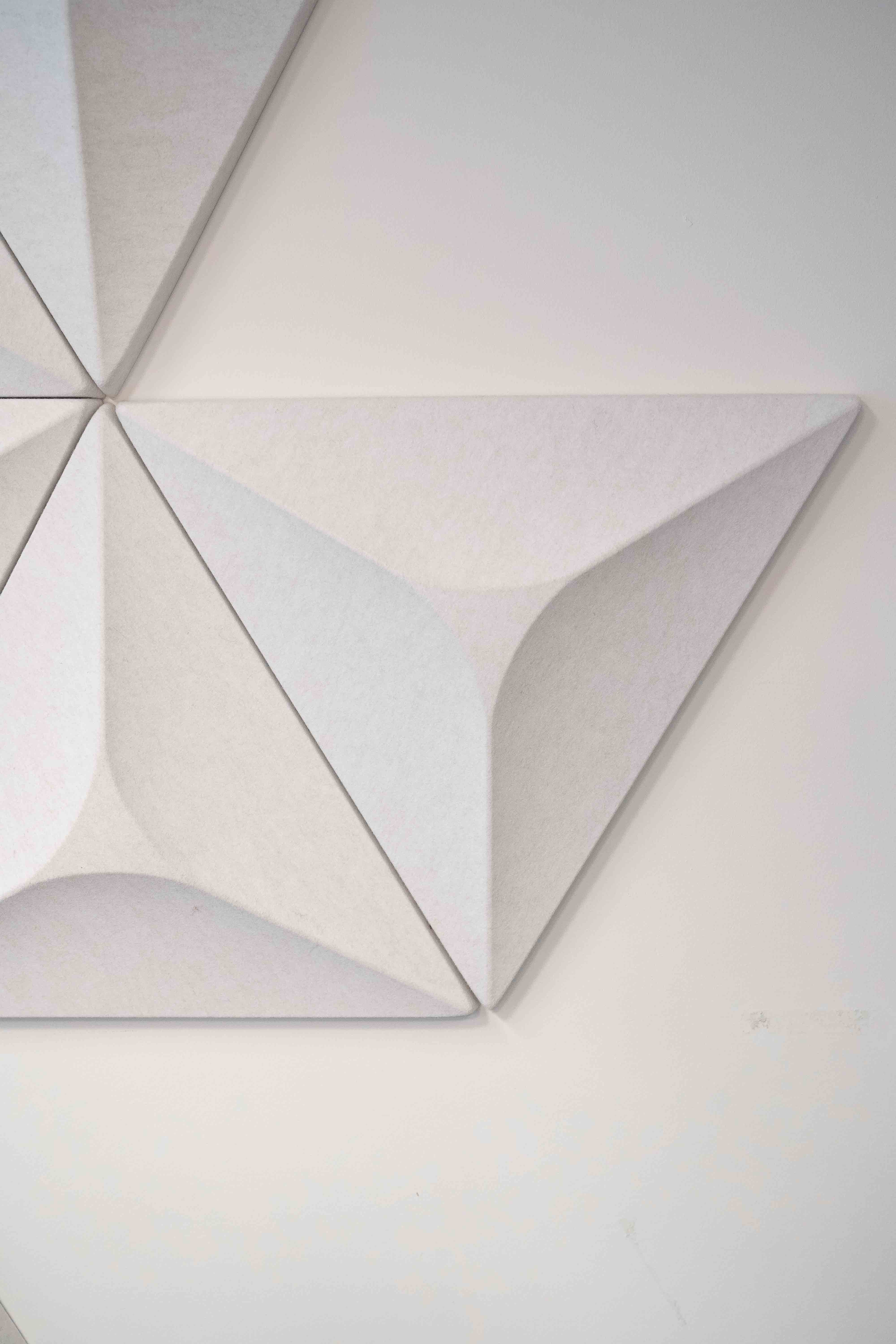 Panneaux muraux acoustiques blancs à motif géométrique.