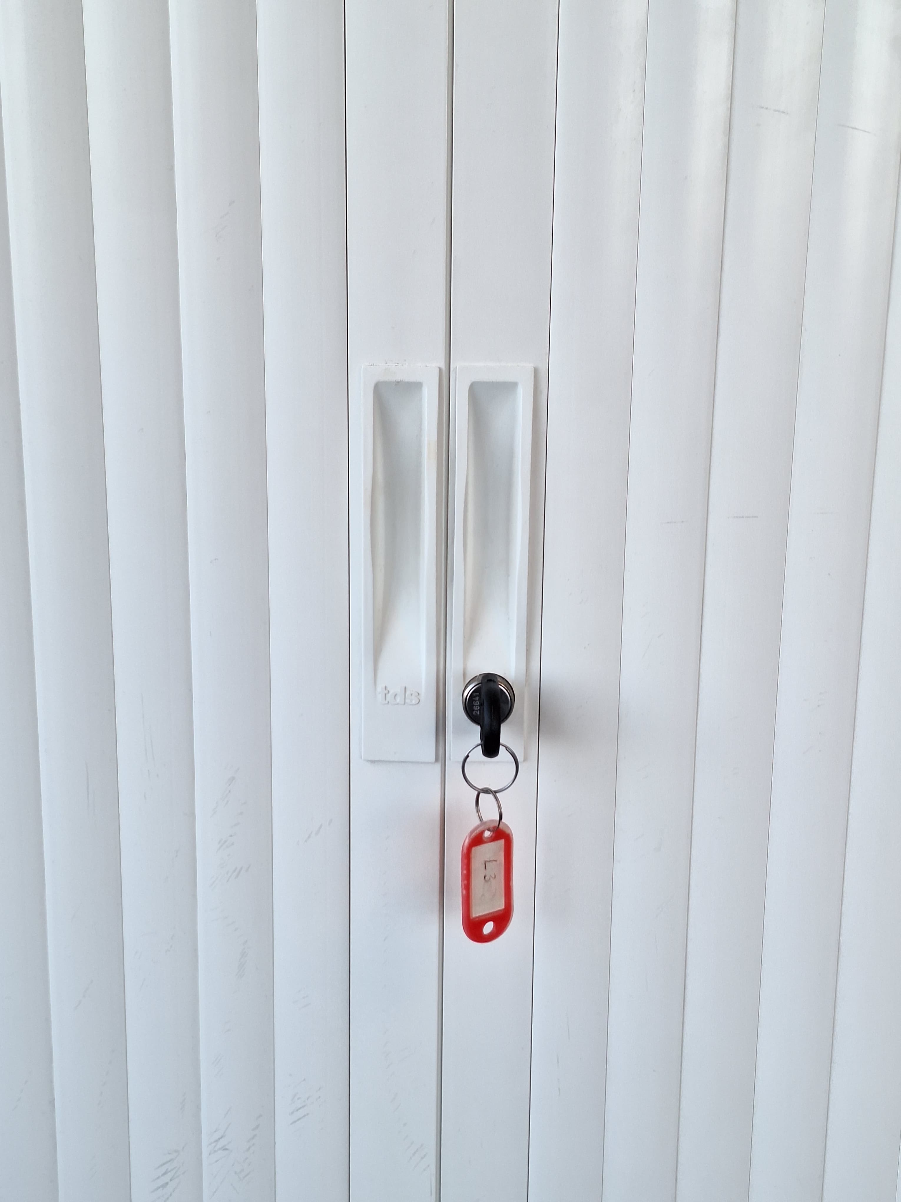 White metal storage cabinet with sliding doors with acoustic panel